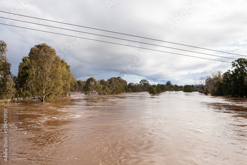 wide brown river full of floodwater during natural disaster flood