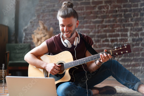 Caucasian young adult learning guitar online music class with distant teacher computer mobile device