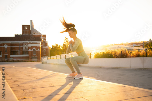 Fotografija Sporty woman doing jumping squats exercises on stairs in park