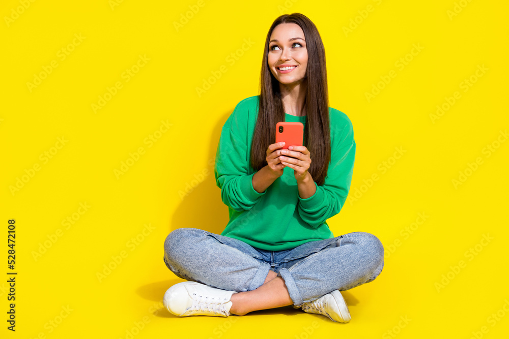 Full body photo of lovely young lady hold device look empty space banner wear stylish green sportswear isolated on yellow color background Full body photo of lovely young lady hold device look empty space banner wear stylish green sportswear isolated on yellow color background