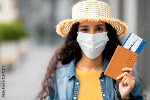 Closeup of woman in face mask holding passport and tickets © Prostock-studio