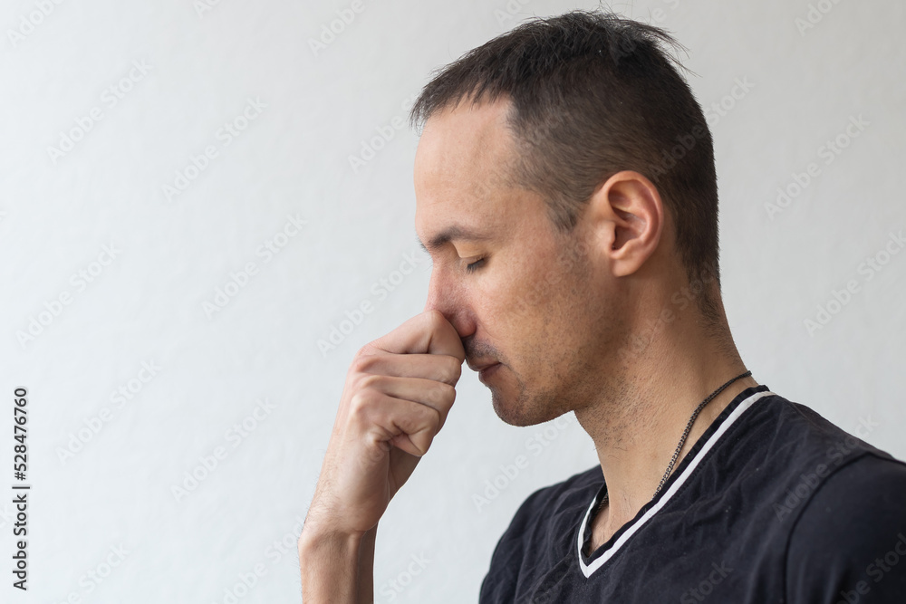 Man smells something stinky and pinches his nose to stop the bad odor Man smells something stinky and pinches his nose to stop the bad odor