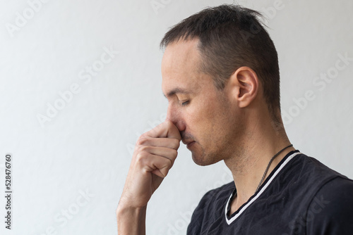Man smells something stinky and pinches his nose to stop the bad odor
