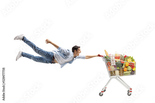 Foto Full length shot of a casual young man flying and holding a shopping cart with f