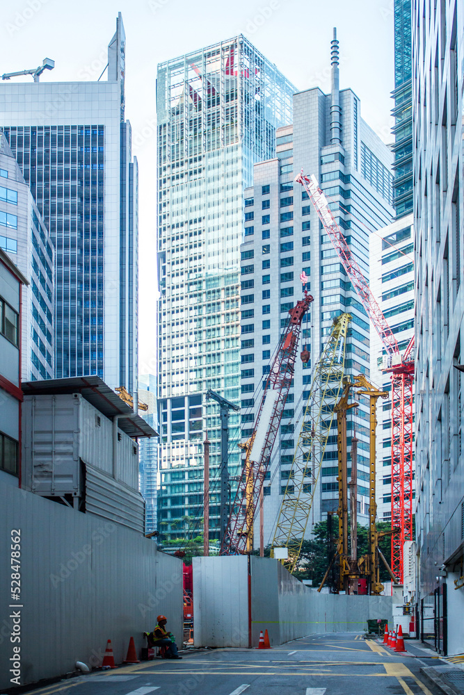 Naklejka premium Tower cranes in construction site among skyscrapers