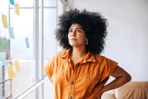 Pensive young businesswoman standing next to a glass wall