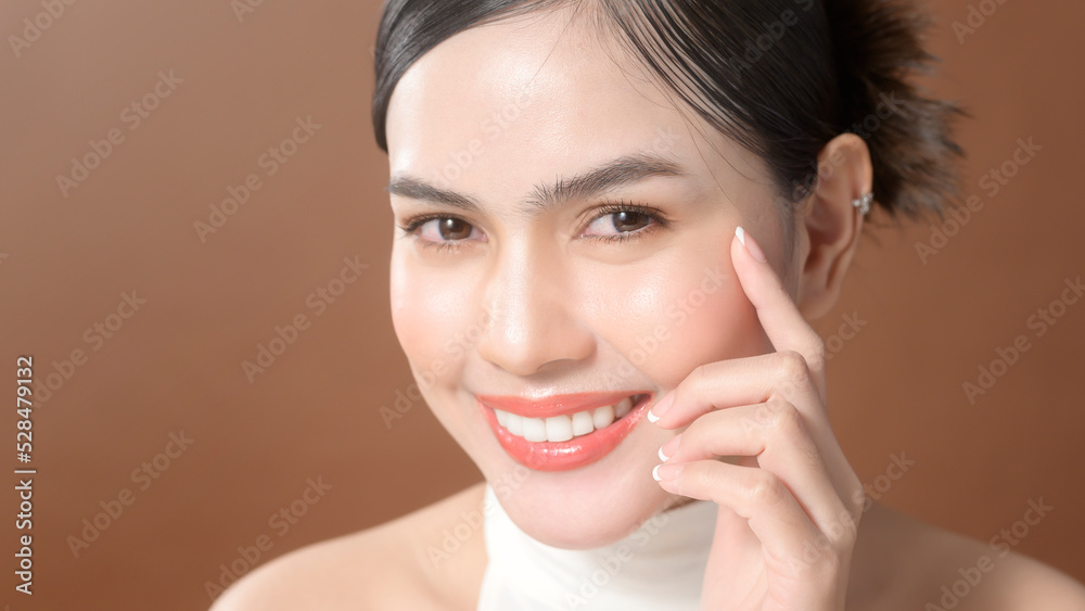 A young woman with beautiful face smiling , touching her face over brown background , beauty skin care concept A young woman with beautiful face smiling , touching her face over brown background , beauty skin care concept