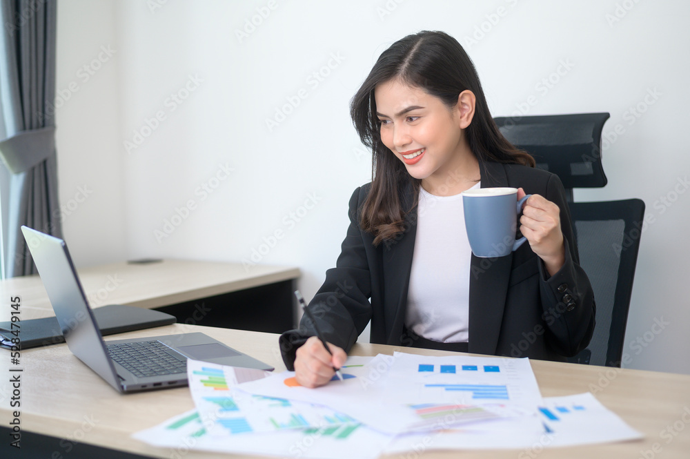 Young beautiful business woman working on laptop with documents in modern office Young beautiful business woman working on laptop with documents in modern office