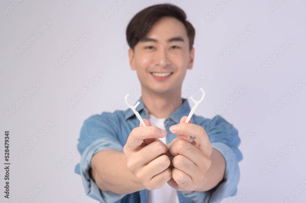 Young smiling man holding dental floss over white background studio, dental healthcare and Orthodontic concept.. Young smiling man holding dental floss over white background studio, dental healthcare and Orthodontic concept..