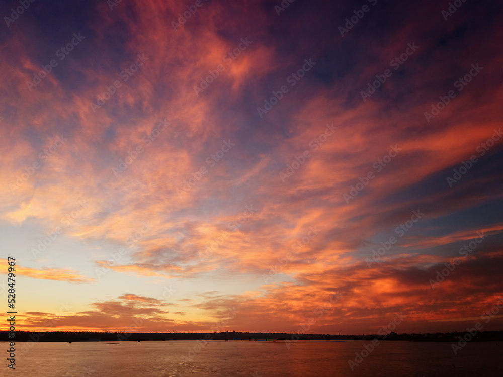 A unique sunset on the shore of the lake with red clouds