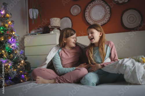 Two Cute sibling children in pajamas on bed in bedroom , christmas, dark style.