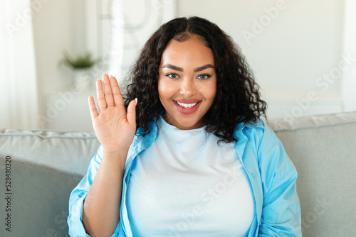 Cheerful African American Female Waving Hand Sitting At Home