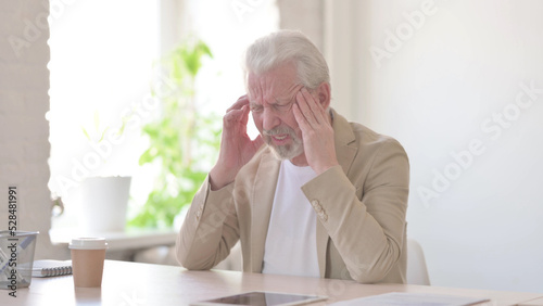 Old Man having Headache while Sitting at work