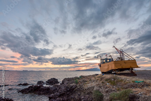 Ship wreck at coast, damaged boat on sunset with colorful sunset sky and clouds