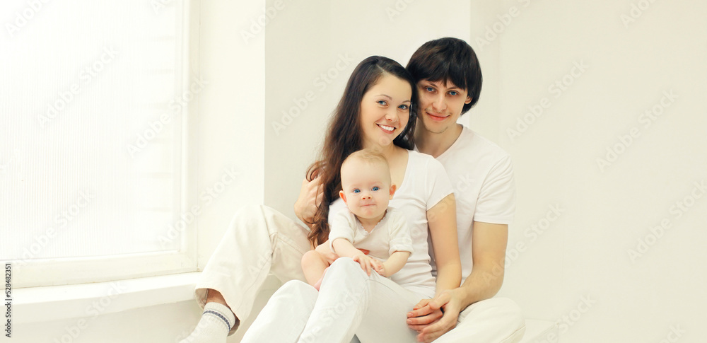 Family portrait of happy mother, father and baby at home in the room