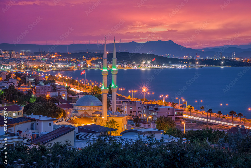 Fototapeta premium Colorful city by sunset, aliaga gulf with a colorful sunset clouds and lights