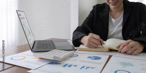 Close-up of business woman hand using a calculator and take notes to check company finances and earnings and budget.