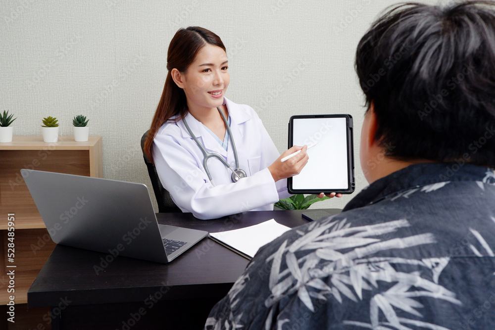 Asian female doctor uses digital tablet to provide online consultation with patients in hospital examination room.แ Asian female doctor uses digital tablet to provide online consultation with patients in hospital examination room.แ