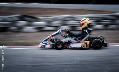 Fotografiet Go kart racing field, racer wearing safety uniform on competition tournament