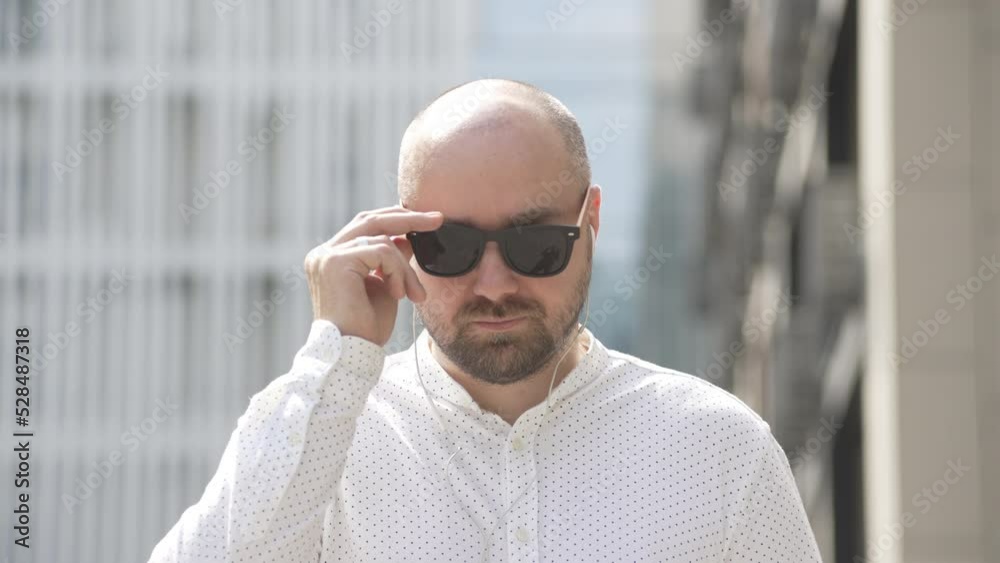 Close-up of a man in casual clothes taking off his sunglasses. A businessman goes to work near the business center. High quality 4k footage Close-up of a man in casual clothes taking off his sunglasses. A businessman goes to work near the business center. High quality 4k footage