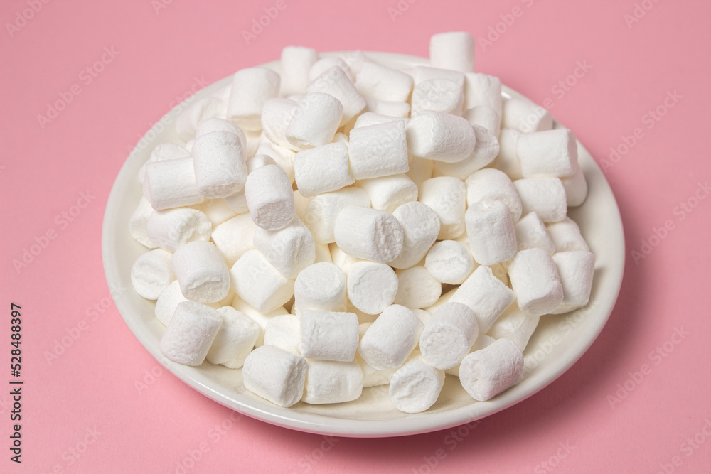 Mini marshmallows on a pink background. A plate full of marshmallows. Dessert ingredient Mini marshmallows on a pink background. A plate full of marshmallows. Dessert ingredient