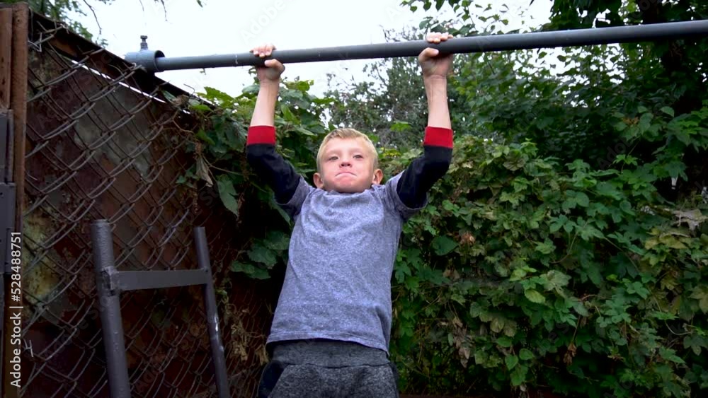 the boy does sports on the horizontal bar in the yard the boy does sports on the horizontal bar in the yard