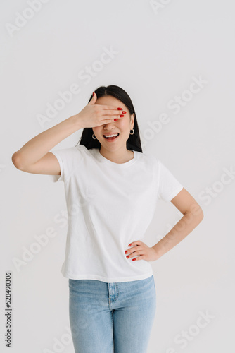 Asian smiling woman wearing t-shirt covering her eyes © Drobot Dean
