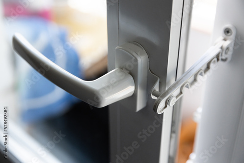 Close-up of a white pvc balcony door handle, an insulating glass window comb fixes the sash. Fittings for child protection and safe ventilation