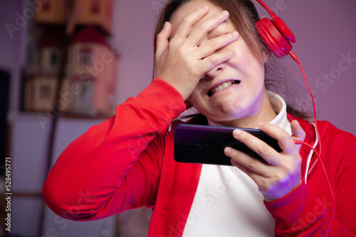 Fotografi Asian women gamer with headphone playing mobile game on the smartphone online