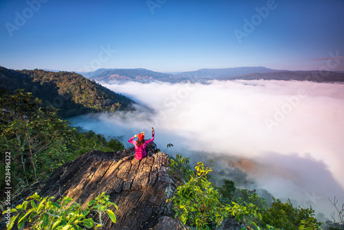 Young woman in red jacket hiking on Pha Muak mountain, border of Thailand and Laos, Loei province, Thailand. © Nakornthai