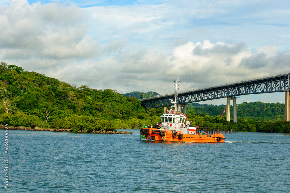 Westbound tugboat on the Panama canal under bridge of the Americas, Puente de las Americas