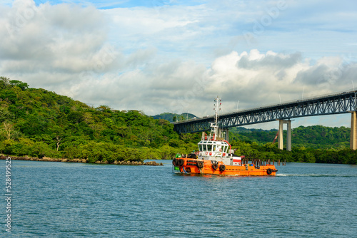 Westbound tugboat on the Panama canal under bridge of the Americas, Puente de las Americas