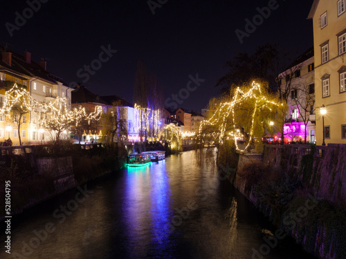The Ljubljanica river in colorful Christmas time with a boat on the river. Long exposure