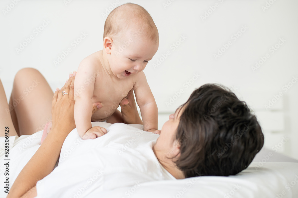 happy family. Mother and baby playing and smiling on bed happy family. Mother and baby playing and smiling on bed