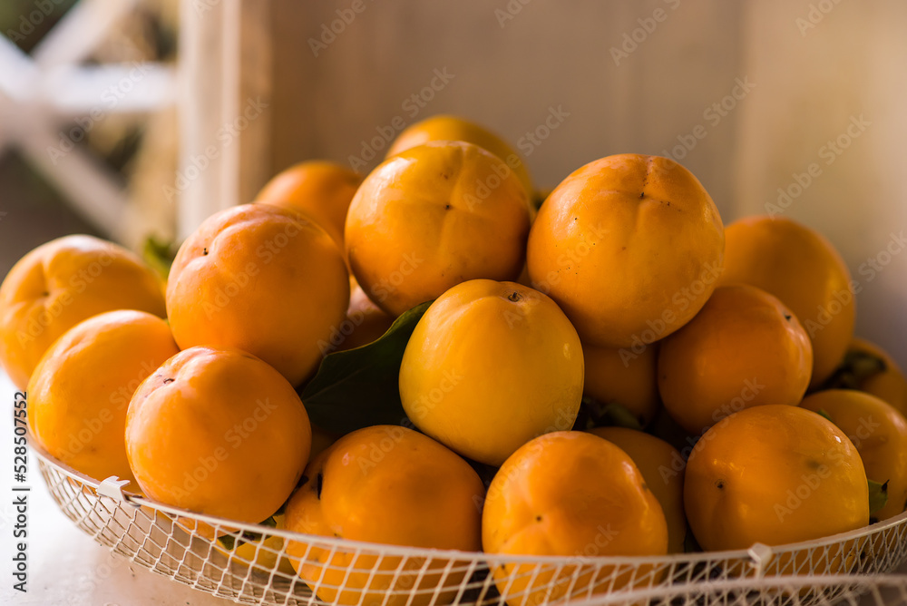 Persimmons or Persimon fruits in wooden bowl with slice isolated on old wooden table background. Persimmons or Persimon fruits in wooden bowl with slice isolated on old wooden table background.