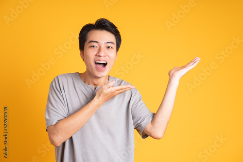 Asian young man posing on a yellow background