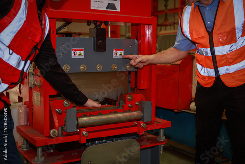 The manager is explaining the precautions and safety warning signs. attached to the machine for the engineering team