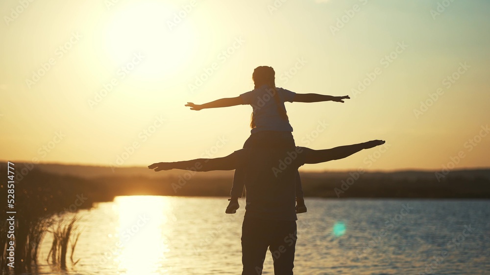 Father and daughter. daughter sits on dads neck silhouette in a field in the park. happy family childhood dream concept. father and daughter play pilots , dreaming of showing fun the plane lifestyle