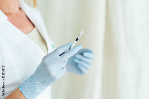 Cosmetologist in sterile gloves holds syringe for injection with collagen hyaluronic filler for face or lips rejuvenation