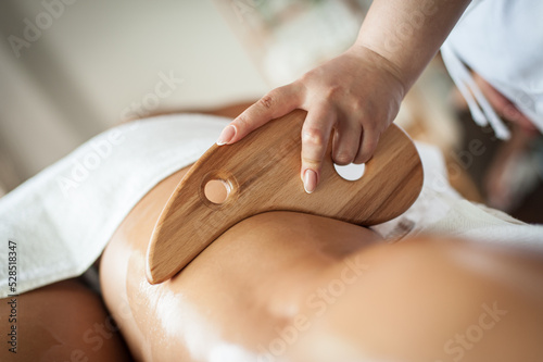 Foto A female therapist performs maderotherapy on a woman's legs with a wooden massag