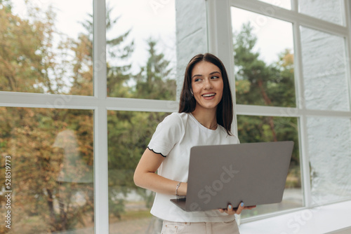 Working from home. Young girl using laptop for online video call or web conference with boss while sitting on windowsill