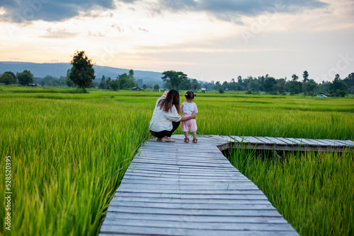 Mother and daughter doing activities together, walking to see the beautiful rice fields and mountains during the sunset time.