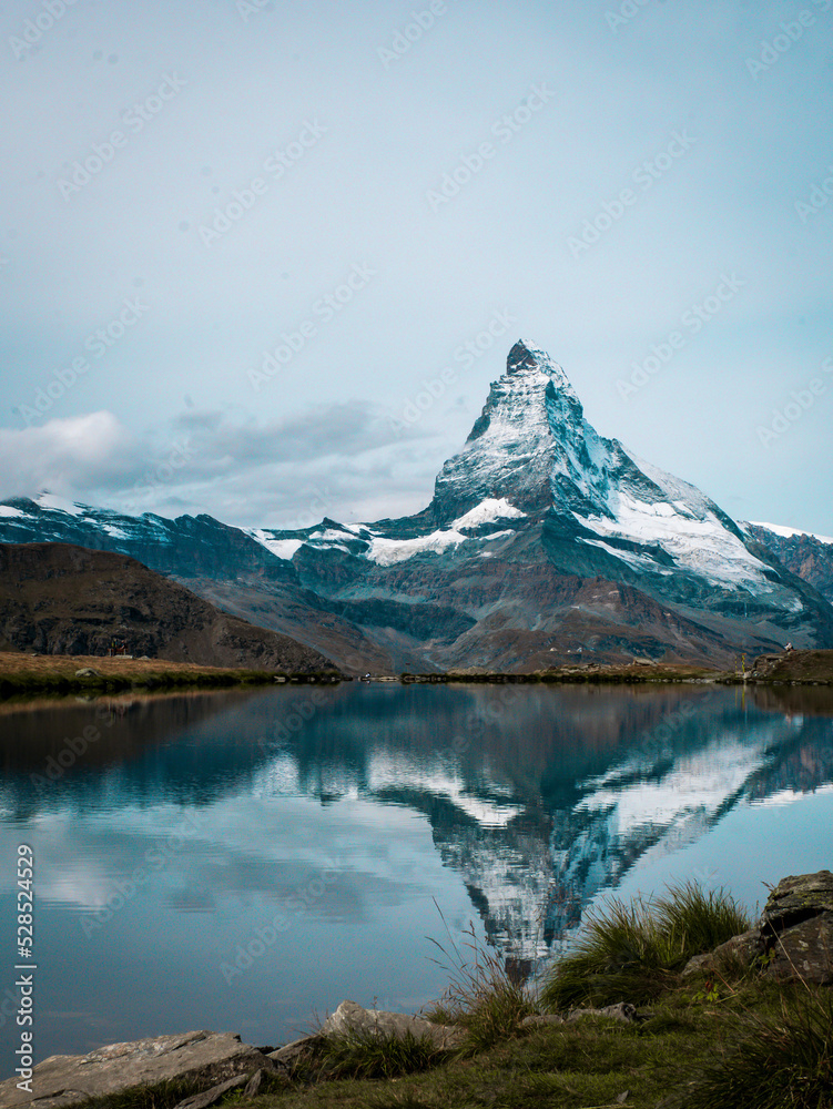 The snowy peak of the Matterhorn in Switzerland is reflected in the surface of a mountain lake