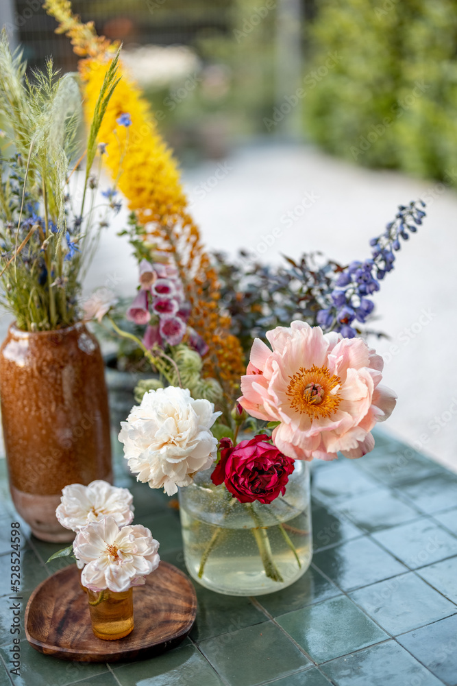 Garden table decorated with different cut flowers in vases