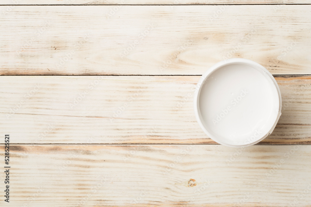 Open paint bucket on wooden background, top view Open paint bucket on wooden background, top view
