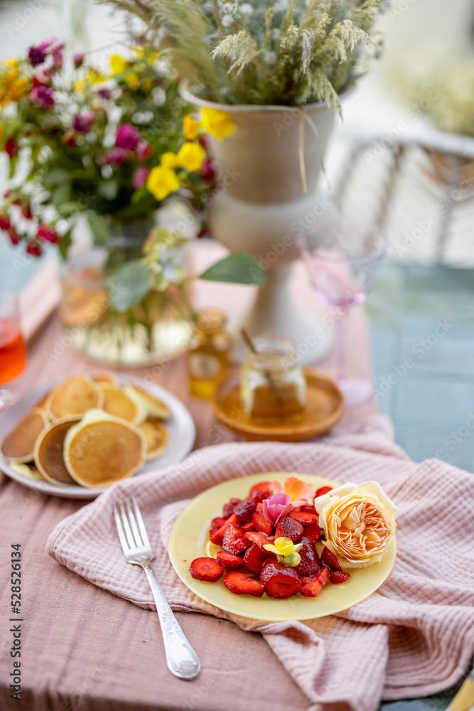 Breakfast on beautifully decorated table with flowers in garden Breakfast on beautifully decorated table with flowers in garden