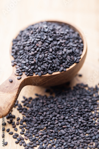 Bio natural black sesame seeds on wooden spoon.