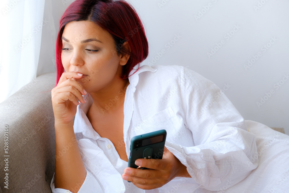 Pretty girl using her smartphone on couch at home in the living room Pretty girl using her smartphone on couch at home in the living room