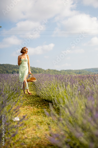 Fototapeta Naklejka Na Ścianę i Meble -  Woman in dress with basket walks on lavender field on sunny day