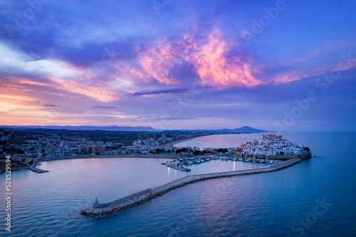 Fotografía aérea desde el sur de Peñíscola durante la hora azul con algunas nubes rosadas en el fondo.
